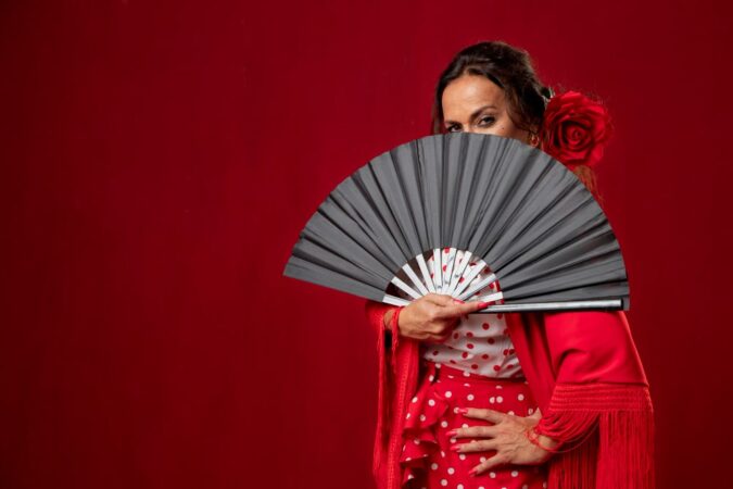 Une femme vêtue d’une tenue rouge traditionnelle tient un éventail noir pas cher et élégant, parfait pour compléter un look raffiné