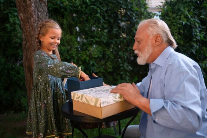Grand-père et petite-fille échangeant des cadeaux innovants et pratiques pour faire plaisir à votre grand-père dans un jardin verdoyant